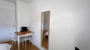 Cette chambre comprend un miroir, une table, une table et une chaise. dans l'établissement Studio Grenoble Universités-Saint Martin D'hères, à Saint-Martin-dʼHères