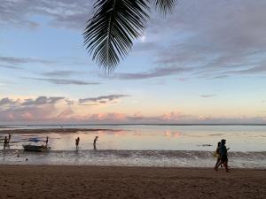 people walking on the beach with a boat in the water at Quarto em frente à praia de Moreré in Moreré