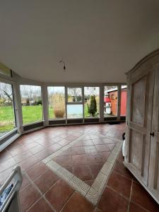 an empty living room with large windows and a tile floor at Ferienhaus Anna in Dagebüll