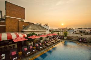 uitzicht op een zwembad van het hotel met stoelen en parasols bij Buddy Lodge, Khaosan Road in Bangkok