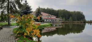 un grand bâtiment avec une maison à côté d'un lac dans l'établissement Villa Dudziak, à Słubice