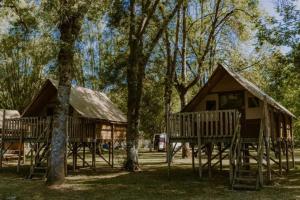 a couple of cottages in the woods with trees at Camping Onlycamp Le Sabot in Azay-le-Rideau