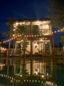 une maison éclairée la nuit en face d'une piscine dans l'établissement Kali Village, à Acapulco