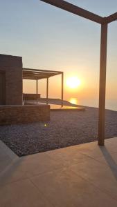 a picnic shelter on the beach with the sunset at Thermyes Villas 3 in Kithnos