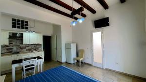 a kitchen with white cabinets and a table and a refrigerator at Lu Salentu White House in Marina di Mancaversa