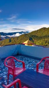 twee rode stoelen op een balkon met uitzicht bij Hotel Tourist Home By palak Hospitality in Mussoorie