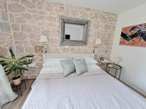 a bedroom with a large bed with a stone wall at Guest House Kala in Split