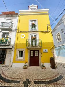un bâtiment jaune avec des fleurs devant lui dans l'établissement Baia do Mundo, à Setúbal