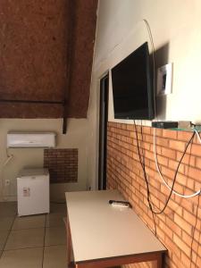 Zimmer mit einem Tisch und einem TV an einer Backsteinwand in der Unterkunft Pousada Vereda das Aguas in Ponte Alta do Tocantins