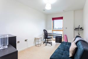 a living room with a blue couch and a desk at Trendy Queen's Park Apartment with Views across London in London