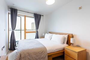 a bedroom with a bed and a large window at Trendy Queen's Park Apartment with Views across London in London