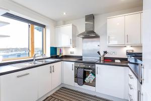 a kitchen with white cabinets and a sink and a window at Trendy Queen's Park Apartment with Views across London in London