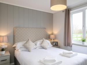 a bedroom with a white bed with two towels on it at Penmarlam Lodge Retreat 5 in Fowey