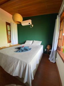 ein Schlafzimmer mit einem großen weißen Bett und einer grünen Wand in der Unterkunft Saudade da Bahia in Moreré