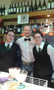 a man and two women wearing bow ties standing in front of a bar at Albergo Caprile in Uscio