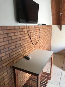 a table with a television on a brick wall at Pousada Vereda das Aguas in Ponte Alta do Norte