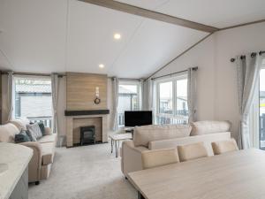 sala de estar con muebles blancos y chimenea en Penmarlam Lodge Retreat 18 en Fowey