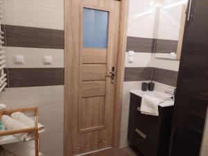 a bathroom with a wooden door and a sink at Apartament Happy Stay in Rzeszów