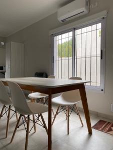 une table à manger avec des chaises blanches et une fenêtre dans l'établissement Departamento los patitos, à Lobos
