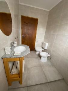 a bathroom with a toilet and a sink and a mirror at Departamento los patitos in Lobos +6 photos