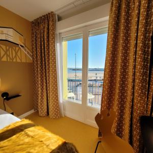 een slaapkamer met een raam met uitzicht op de oceaan bij Seakub hotel in Royan