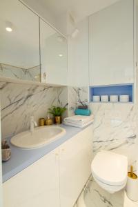 a white bathroom with a sink and a toilet at Nowy Apartment przy Placu Szembeka in Warsaw