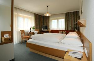 アウ・イム・ブレゲンツァーヴァルトにあるHaus Alpinaのベッド、テーブル(デスクシックス付)が備わる客室です。
