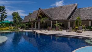 a resort pool with chairs and a building at The Mayana Resort in Dauis