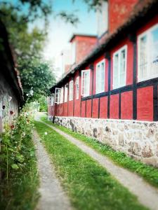 a red and black building with a stone wall at Pension Sandbogaard in Sandvig