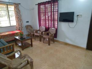 a living room with chairs and a flat screen tv at Homely Home stay in Kalpetta