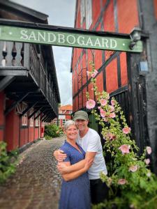 un hombre y una mujer de pie bajo un letrero de la calle en Pension Sandbogaard, en Sandvig