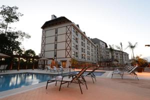 um hotel com piscina e cadeiras e um edifício em Vista Azul Apart Hotel - Vista Pedra Azul com Cozinha Compacta em Domingos Martins