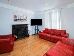 a living room with a red couch and a television at 11 Magdalene Road in Torquay