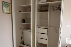 a closet with white shelves and a refrigerator at Nowy Apartment przy Placu Szembeka in Warsaw
