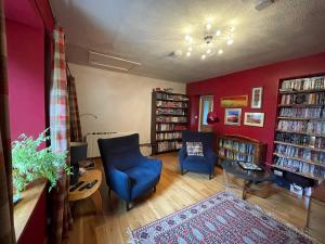 una sala de estar con 2 sillas azules y una pared roja en One bed cosy Highland cottage near Beauly, en Beauly