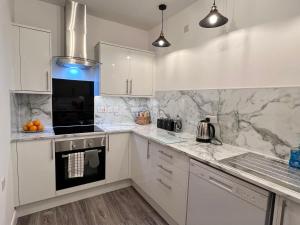 a kitchen with white cabinets and marble counter tops at Sandy shoes in Scarborough