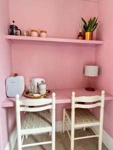 Riversdale House Bed & Breakfast في لانغولين: غرفة وردية مع طاولة وكرسيين