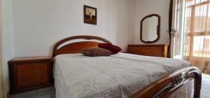 una camera da letto con letto con testiera in legno e specchio di La Stanza di Nunziatina a Ischia