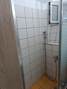 a bathroom with a shower with white tiles at Two-storey maisonette next to the port in Mantoúkion