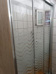 a shower with a glass door in a bathroom at Two-storey maisonette next to the port in Mantoúkion