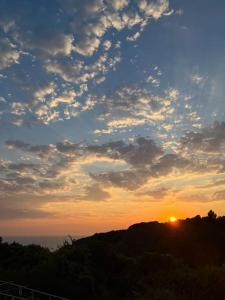 a sunset with the sun setting on top of a hill at Rodovani Cottage in Antípaxos