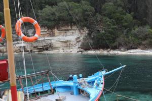 a blue boat in the water with an orange life preserver at Rodovani Cottage in Antípaxos