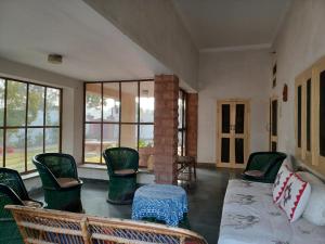Roda House - a boutique homestay in Bikaner في بيكانير: غرفة معيشة مع كراسي وأريكة ونوافذ