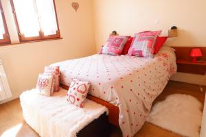 1 dormitorio con 1 cama con almohadas rojas y rosas en Petit chalet de montagne avec espace extérieur, en Labaroche