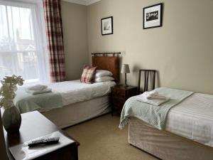 a hotel room with two beds and a window at Bryn Noddfa in Morfa Nefyn