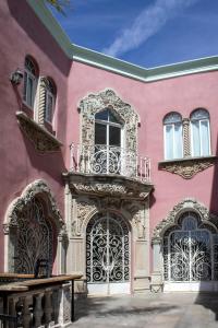 a pink building with two gates and a balcony at Hotel Gran Domo in León