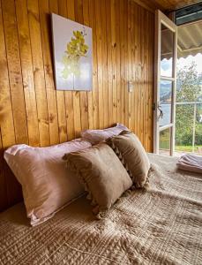 a bed with pillows in a room with a wooden wall at La Carreta in Aquitania