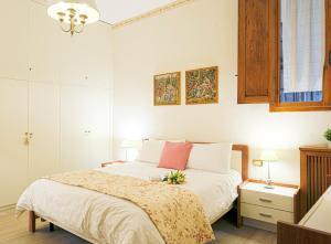 um quarto com uma cama com lençóis brancos e almofadas cor-de-rosa em The Heart of Florence em Florença