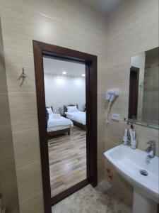 baño con lavabo, espejo y cama en Ayvan Plaza hotel, en Bukhara