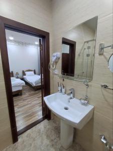 baño con lavabo, espejo y cama en Ayvan Plaza hotel, en Bukhara